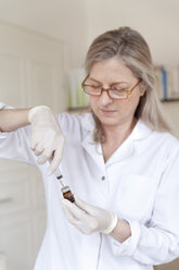 Heilpraktikerin bereitet Injektionsspritze vor - TCF003758