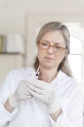 Heilpraktikerin bereitet Injektionsspritze vor - TCF003760