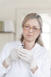 Female alternative practitioner preparing injection syringe - TCF003760