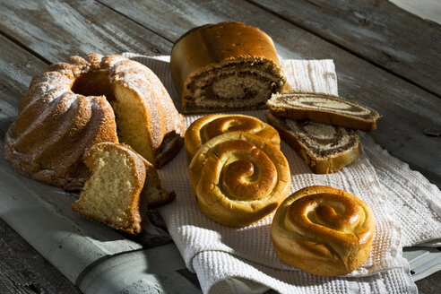 Nussbrötchen, Gugelhupf und Hefegebäck auf Holztisch - MAEF007516