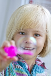 Portrait of smiling little girl with soap bubble - JFEF000257