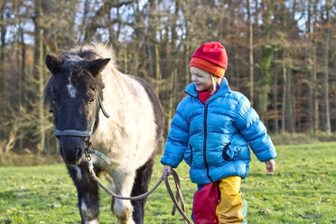 Kleines Mädchen mit Pony auf einer Wiese - JFEF000267