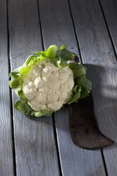 Blumenkohl (Brassica oleracea var. botrytis L.) und antikes Messer auf grauem Holztisch - CSF020590