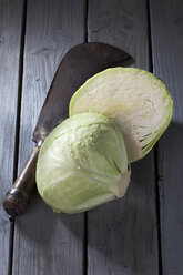 In Scheiben geschnittener Weißkohl (Brassica oleracea convar. capitata var. alba) und antikes Schneidemesser auf grauem Holztisch - CSF020540