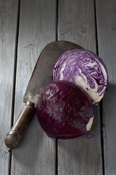 In Scheiben geschnittener Rotkohl ((Brassica oleracea convar. capitata var. rubra L.) und antikes Hackmesser auf grauem Holztisch - CSF020539