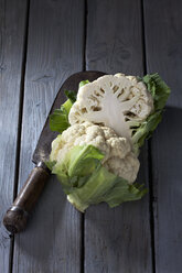 In Scheiben geschnittener Blumenkohl (Brassica oleracea var. botrytis L.) und antikes Schneidemesser auf grauem Holztisch - CSF020538