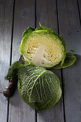 Halbierter Wirsing (Brassica oleracea convar. capitata var. sabauda L.) und antikes Schneidemesser auf grauem Holztisch - CSF020537