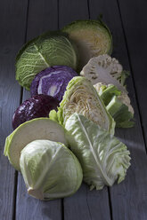 Halved cabbage varieties on grey wooden table - CSF020536