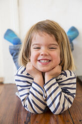 Portrait of little girl lying on wooden floor - LVF000384