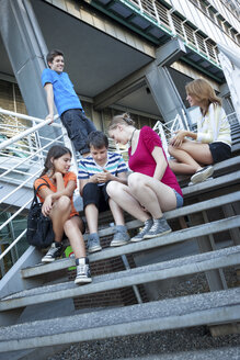 Teenage friends using mobile devices on stairs - MVC000049