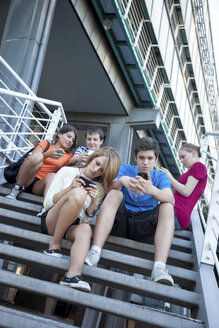 Teenage friends using mobile devices on stairs - MVC000051