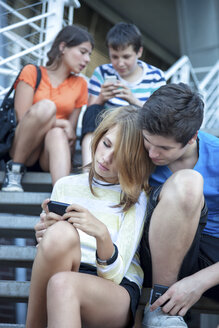 Teenage friends using mobile devices on stairs - MVC000047