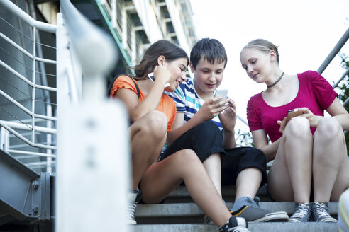 Teenage friends using mobile devices on stairs - MVC000046