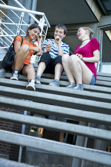 Teenage friends using mobile devices on stairs - MVC000048