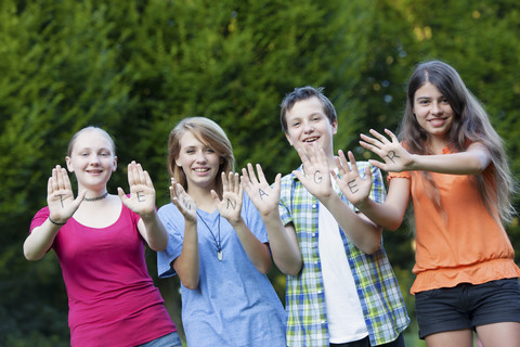 Drei Mädchen und ein Junge zeigen zusammen das Wort Teenager auf ihren Handflächen, lizenzfreies Stockfoto