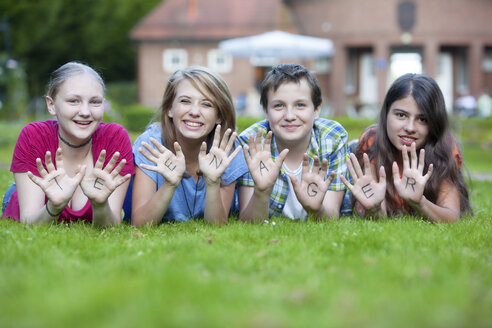 Three girls and one boy showing together the word teenager on their palms - MVC000045