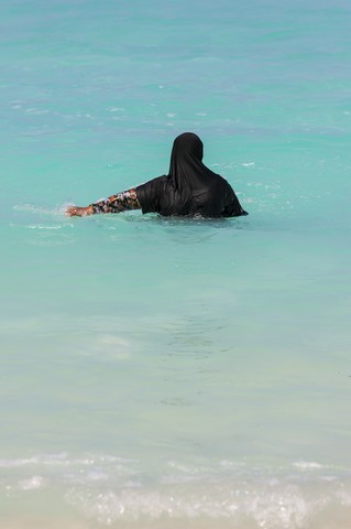Maldives, Muslim woman in the ocean with traditional clothing stock photo