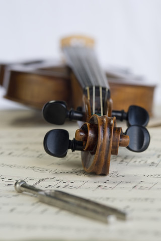 Antike Geige und Stimmgabel auf Musiknoten liegend, lizenzfreies Stockfoto