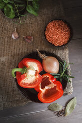 Red bell pepper, red lentils, onions and garlic on wooden table, ingredients for egyptian lentil soup - EVGF000298