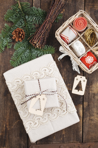 Weihnachtsgeschenk mit Geschenkanhänger und Verpackungsmaterial auf Holztisch, lizenzfreies Stockfoto