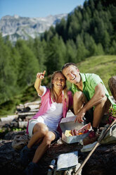 Österreich, Bundesland Salzburg, Altenmarkt-Zauchensee, Pärchen beim Picknick auf Almwiese - HHF004717