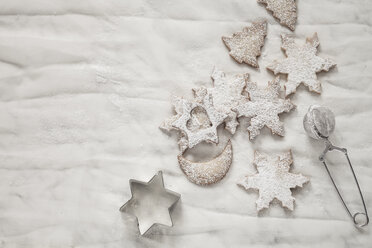 With powdered sugar sprinkled Christmas cookies, strainer and cookie cutter on white ground - SBDF000355