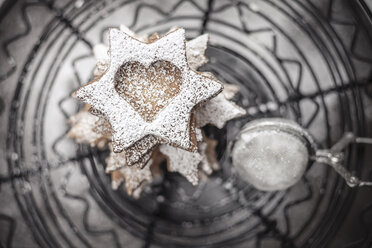 With powdered sugar sprinkled Christmas cookies and strainer lying on cake stand, close-up - SBDF000359