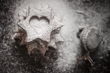 With powdered sugar sprinkled Christmas cookies and strainer on wooden table - SBDF000361