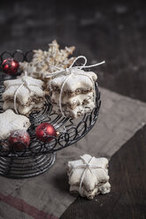 With powdered sugar sprinkled star-shaped cinnamon cookies and red Christmas baubles on cake stand - SBDF000373