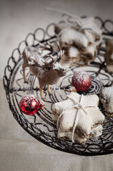 Mit Puderzucker bestreute Zimtsterne, Miniaturhirsche und rote Weihnachtskugeln auf einem Tortenständer - SBDF000376