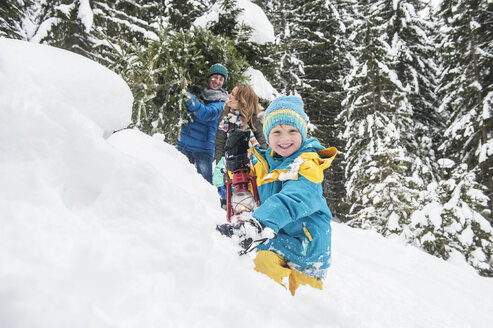 Österreich, Salzburger Land, Altenmarkt-Zauchensee, Familie geht im Schnee spazieren, trägt Weihnachtsbaum - HHF004665