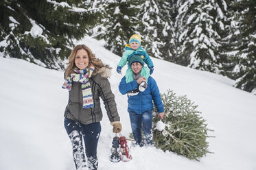 Österreich, Salzburger Land, Altenmarkt-Zauchensee, Familie geht im Schnee spazieren, trägt Weihnachtsbaum - HHF004666