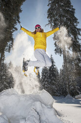 Österreich, Bundesland Salzburg, Altenmarkt-Zauchensee, Frau mit Schneeschuhen springt in Winterlandschaft - HHF004694