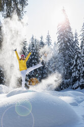 Österreich, Bundesland Salzburg, Altenmarkt-Zauchensee, Frau mit Schneeschuhen springt in Winterlandschaft - HHF004695