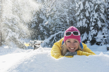 Österreich, Land Salzburg, Altenmarkt-Zauchensee, Lächelnde junge Frau im Schnee liegend, Porträt - HHF004674