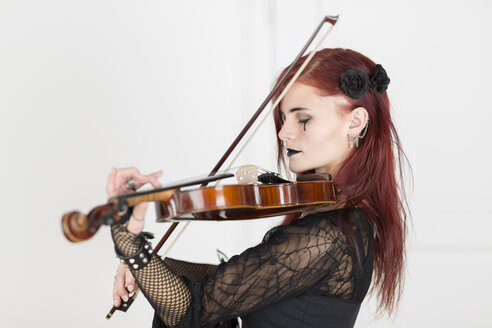 Junge Frau im gotischen Stil gekleidet spielt Geige mit geschlossenen Augen - DRF000353