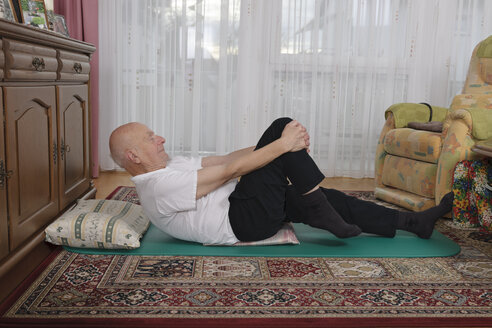 Alter Mann macht Übungen in seinem Wohnzimmer - LAF000393