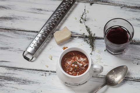 Tomatensuppe mit Parmesan, Rotwein, Parmesankäse mit Reibe, Thymian auf Holztisch, lizenzfreies Stockfoto