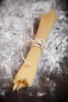 Ein Bündel Spaghetti auf einem Holztisch mit Mehl - SBDF000397