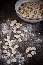 Orecchiette in einer Schüssel und auf einem Holztisch mit Mehl - SBDF000391