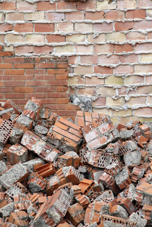 Spain, Catalonia, building site, heap of bricks at wall - JMF000278
