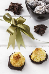 Bowl of coco chocolate truffles, coco macaroons and chocolate almond slivers on white wooden table, studio shot - EVGF000308