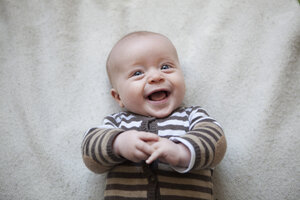 Porträt eines lachenden kleinen Jungen auf einer Decke liegend, Ansicht von oben - RBF001602
