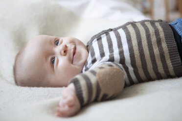 Porträt eines glücklichen kleinen Jungen auf einer Decke liegend - RBF001604
