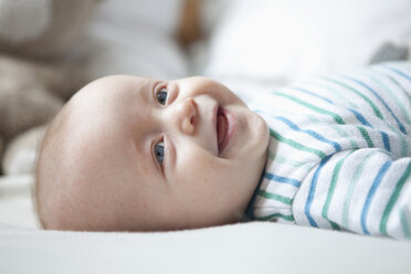 Portrait of laughing baby boy lying on blanket - RBF001605