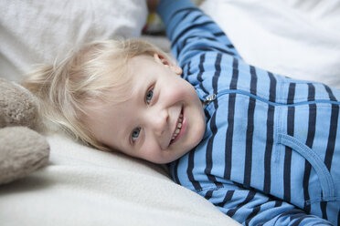 Porträt eines lächelnden kleinen Jungen auf einer Decke liegend - RBF001610