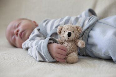 Porträt eines schlafenden kleinen Jungen auf einer Decke mit einem Teddybär - RBF001608