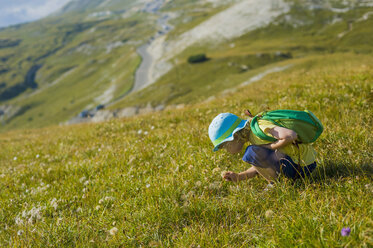 Italy, Province of Belluno, Veneto, Auronzo di Cadore, little boy crouching on alpine meadow near Tre Cime di Lavaredo - MJF000467