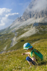 Italy, Province of Belluno, Veneto, Auronzo di Cadore, little boy crouching on alpine meadow near Tre Cime di Lavaredo - MJF000486