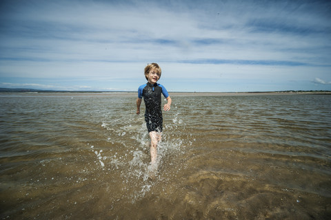 Großbritannien, Schottland, Burghead Bay, Junge läuft im Wasser, lizenzfreies Stockfoto